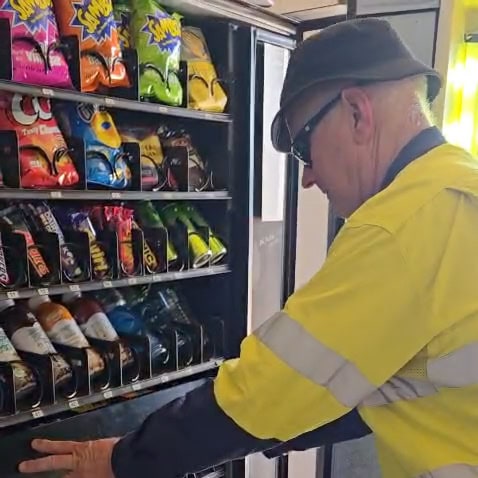 Technician restocking a vending machine on a restocking schedule at a remote WA mine site