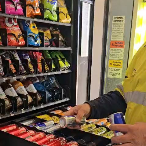 A1 Vending restocking a snack and drink vending machine on a WA site.